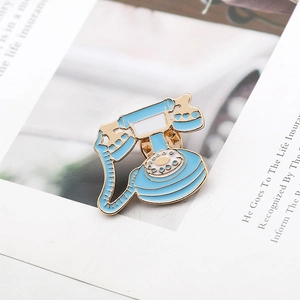 Close-up of vintage light blue enamel telephone brooch with golden metal edges