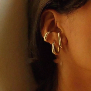 Detailed close-up of three polished gold-plated lava style ear cuffs on a model ear