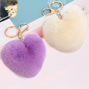 Detailed view of heart-shaped faux fur keychains in purple and cream with gold rings