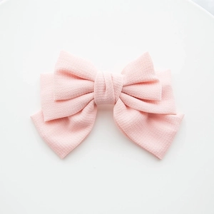 Detail of multi-layered pink fabric bow hair clip with textured seersucker material