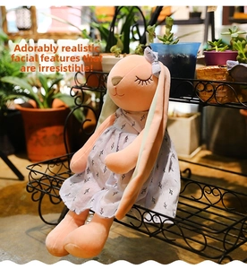 Close-up of pink long-eared bunny plush in a floral dress with closed-eye expression