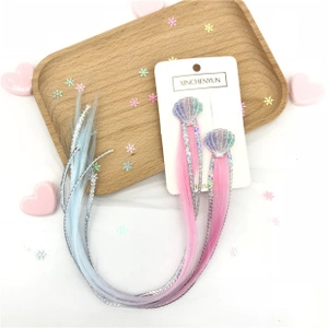 Detail of gradient hair extensions with glitter tinsel and shell-shaped clips on card