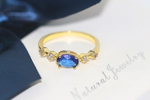 Macro shot of gold ring featuring oval blue gemstone and zircon side stones