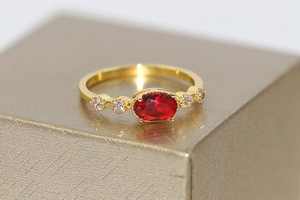 Macro shot of oval red gemstone ring with zircon accents in vintage gold setting