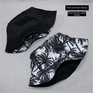 Flat lay view of a reversible black sun hat with palm tree patterns on the alternate side