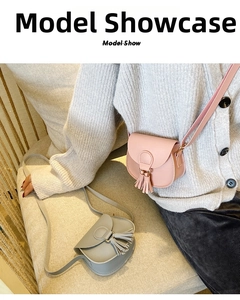 Detailed view of mini saddle bags with tassel accents in pink and grey faux leather