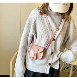 Close-up of a pink mini crossbody bag with tassel detail on a girl's shoulder