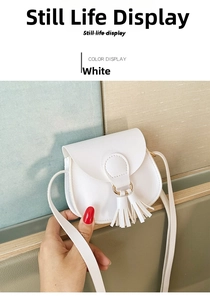 Detail view of mini white crossbody bag featuring elegant leather fringe and gold ring detail