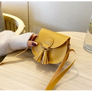Close-up of bright yellow mini crossbody bag with stylish tassel decor and leather strap