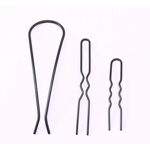 Detail view of black metal U-shaped and wavy hair pins for bun styling on white background