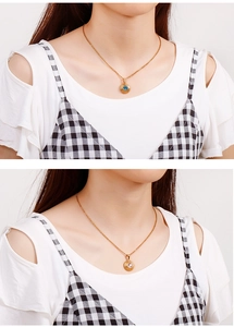 Detail of round gold pendant necklaces featuring blue and white zircon stones on model