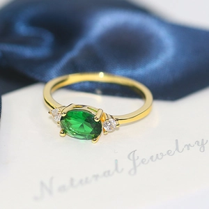 Elegant gold ring featuring a large oval green zircon center stone with clear side gems