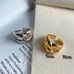 Detail of silver and gold irregular cross rings on a minimalist book background