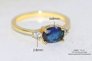 Macro shot of gold ring with 6x8mm blue oval stone and clear side zircons detail