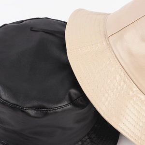 Close-up showing the fine leather texture and stitching of black and beige bucket hats