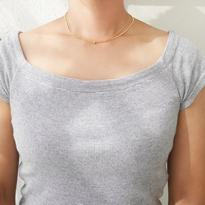 Close-up of double-layer gold necklace featuring minimalist fine chains and small bead details