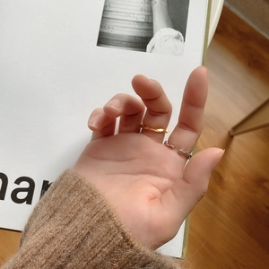 Detail of minimalist wavy gold and silver rings worn on fingers with a cozy style
