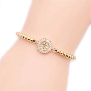 Golden beaded bracelet with micro-pave cross pendant on a model's wrist