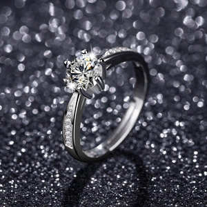 Macro shot of silver ring with six-prong set round zircon on sparkling black background