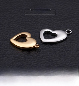 Macro detail of heart-shaped hollow metal pendants in gold and silver on black leather