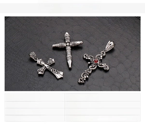 Macro detail of gothic stainless steel cross pendants with red gemstone on leather texture