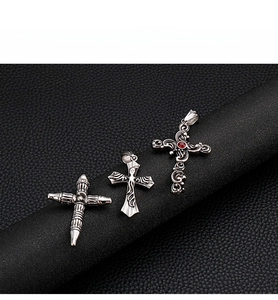 Macro detail of gothic stainless steel cross pendants with vintage relief and red gemstone