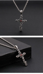 Close-up of gothic silver steel cross pendant with a red gemstone and twisted chain