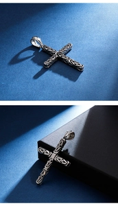 Détail d'un pendentif croix en acier inoxydable argenté avec texture tissée complexe