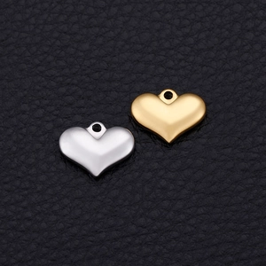 Golden and silver heart-shaped metal charms for DIY jewelry making on leather background
