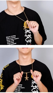 Close-up of a punk gold skull wearing a top hat pendant on a rope chain necklace