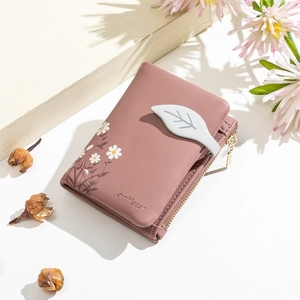 Close-up of pink vegan leather wallet with daisy embroidery and leaf-shaped clasp