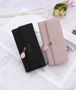 Detail of elegant long wallets with golden leaf charms on marble background