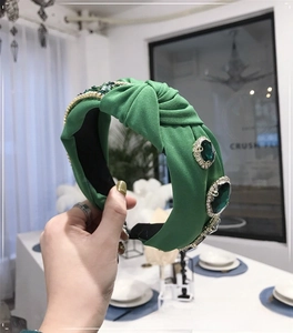 Close-up of baroque knitted headband with emerald gemstones and sparkling crystal details