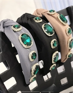 Detail of baroque headbands with emerald crystals and knitted knots on a satin fabric base