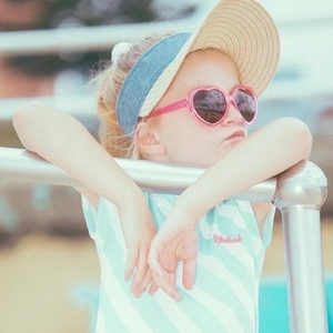 Pink heart-shaped sunglasses for kids with beige straw hat for summer beach vacation