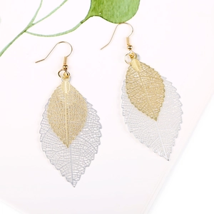 Macro detail of layered gold and silver leaf earrings with intricate hollow veins