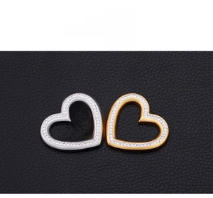 Macro detail of heart-shaped pendants in silver and gold with pavé-set crystals