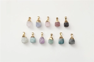 Detailed flat lay of eleven natural raw gemstone pendants with golden metal caps