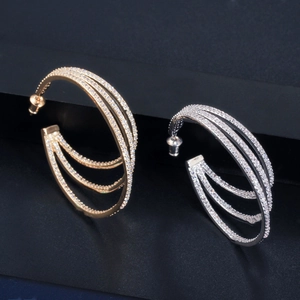 Macro shot of triple-layer C-shaped hoop earrings with micro-pave zircons in gold and silver