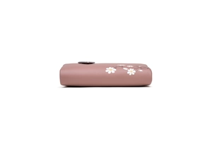 Side view of small pink leather wallet featuring white daisy floral print and button closure