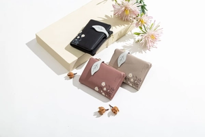 Three compact women's wallets in black, pink and beige featuring floral daisy prints