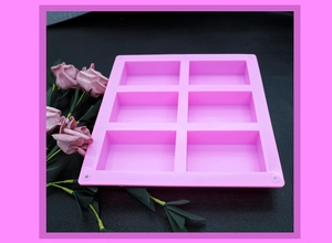 Detalle del molde rectangular de silicona de 6 cavidades rosa sobre fondo de cuero