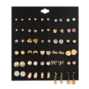 Detailed close-up of 30 pairs of rhinestone floral stud earrings on black card
