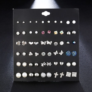 Flat lay of 30 pairs assorted crystal and pearl stud earrings on black card display