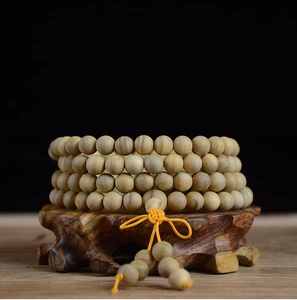 Macro detail of Papua wood 108 prayer beads bracelet on a carved rosewood stand