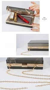 Detail of smoke gray acrylic clutch bag showing interior capacity and golden chain