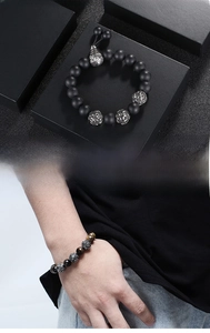Detail view of men's titanium steel bracelet with black lava stone and tiger eye beads