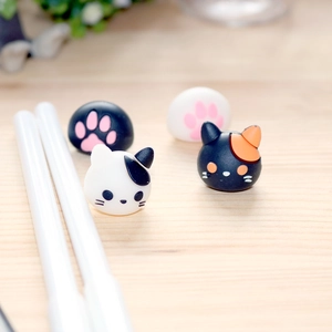 Macro view of cute silicone cat claw and cat face pencil toppers on a wooden desk