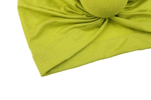 Close-up of grass green knit turban hat with detailed stitching and spherical ornament