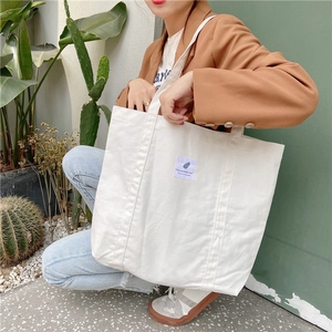 Lifestyle shot of white minimalist canvas tote bag with shoulder straps worn by model